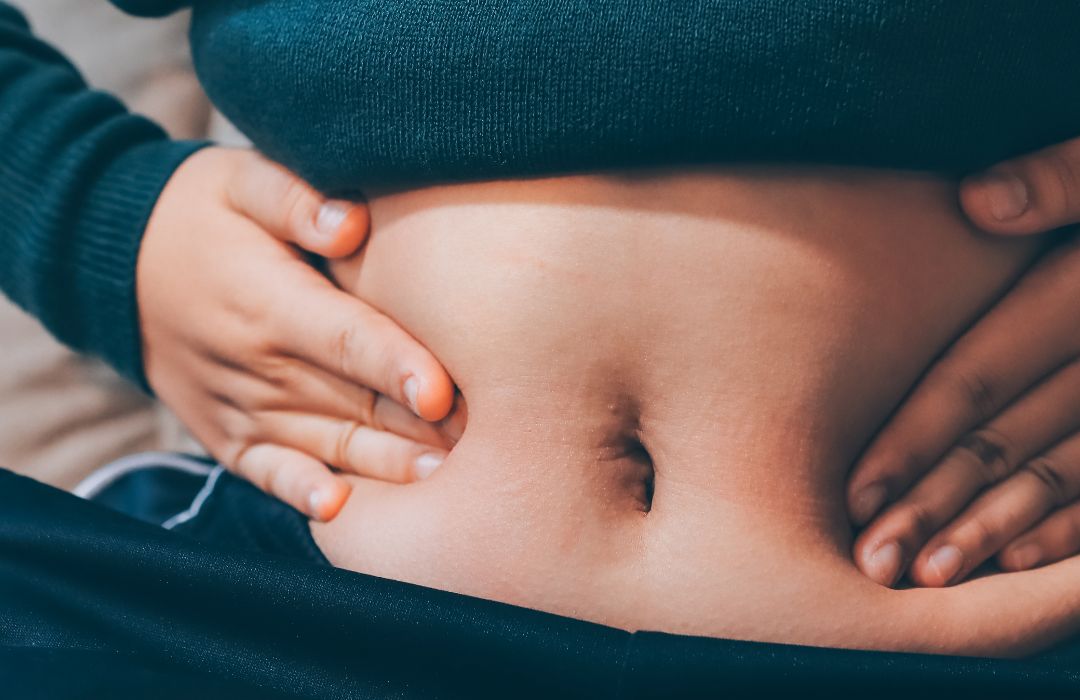 배꼽 주변을 손가락으로 가볍게 확인하는 사람의 복부