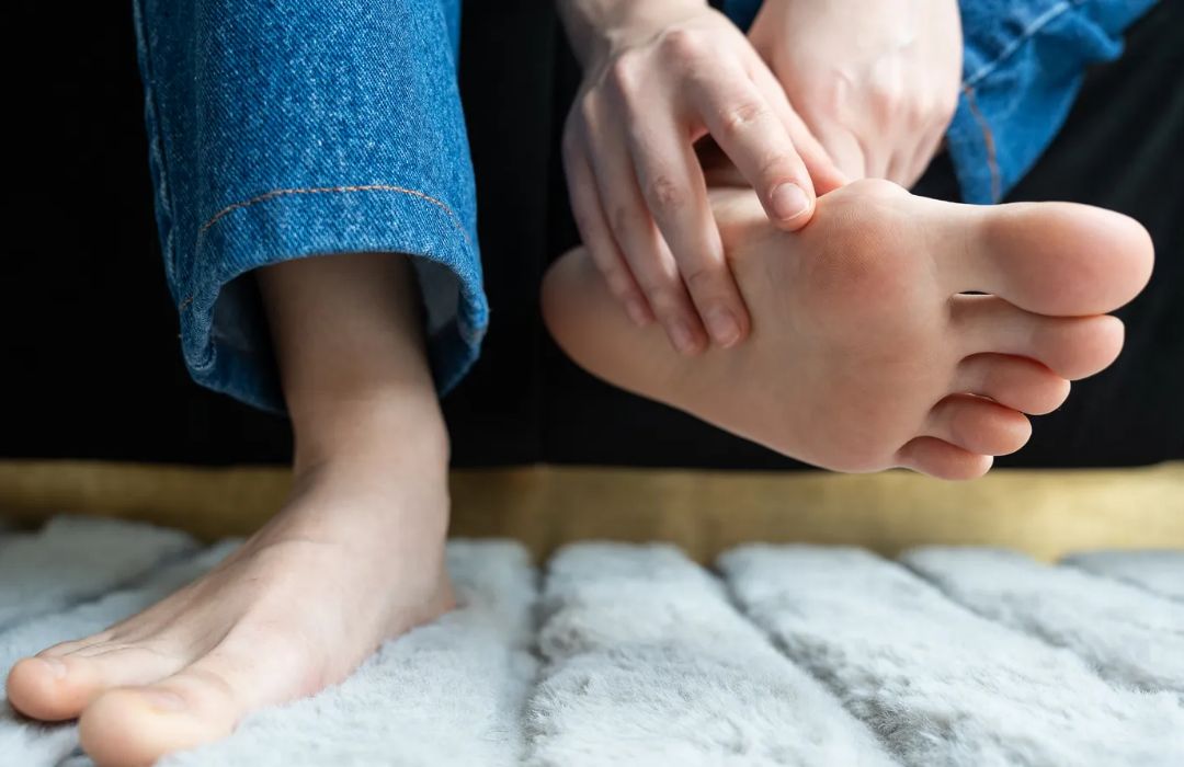 밤에 침대에 앉아 발바닥이 화끈거려 손으로 발을 만지는 사람