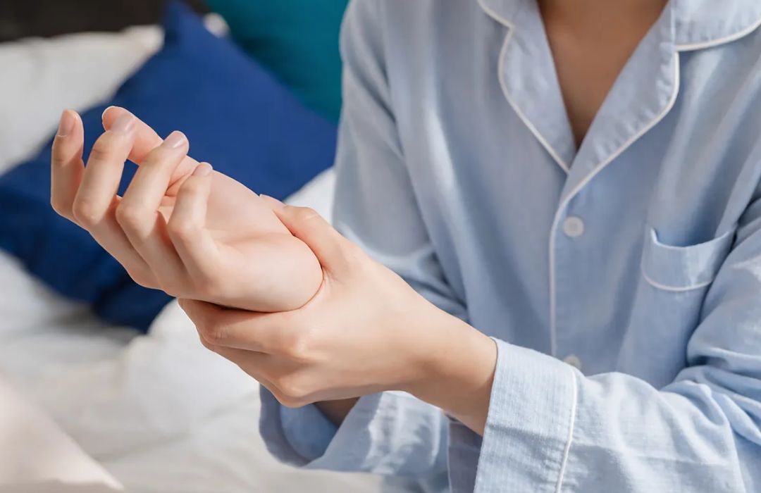 아침에 잠에서 깬 뒤 손목 통증을 느껴 손목을 잡고 있는 사람